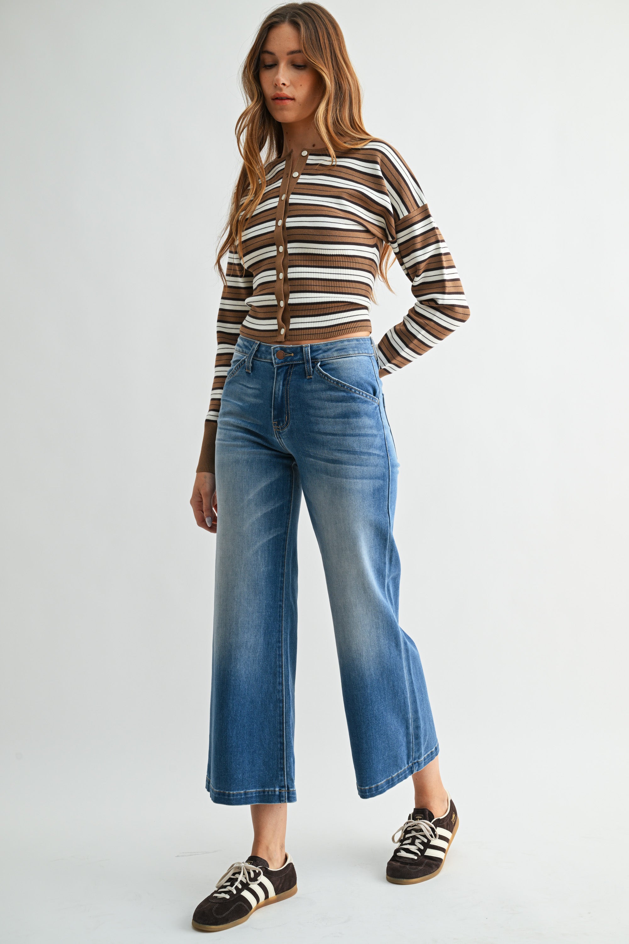 Woman wearing a striped sweater and blue jeans on a white background