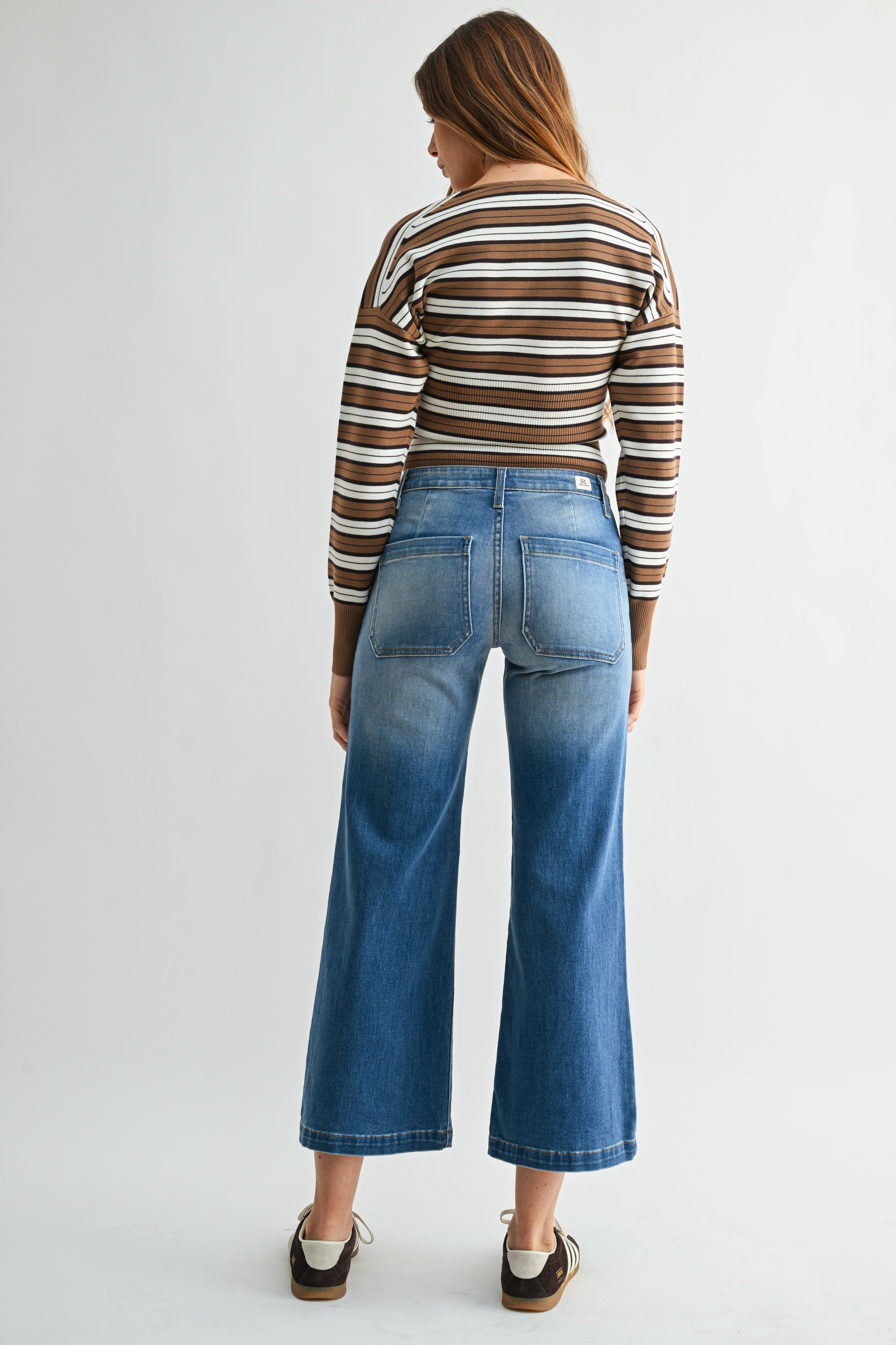 Person wearing a striped long-sleeve shirt and blue jeans on a white background