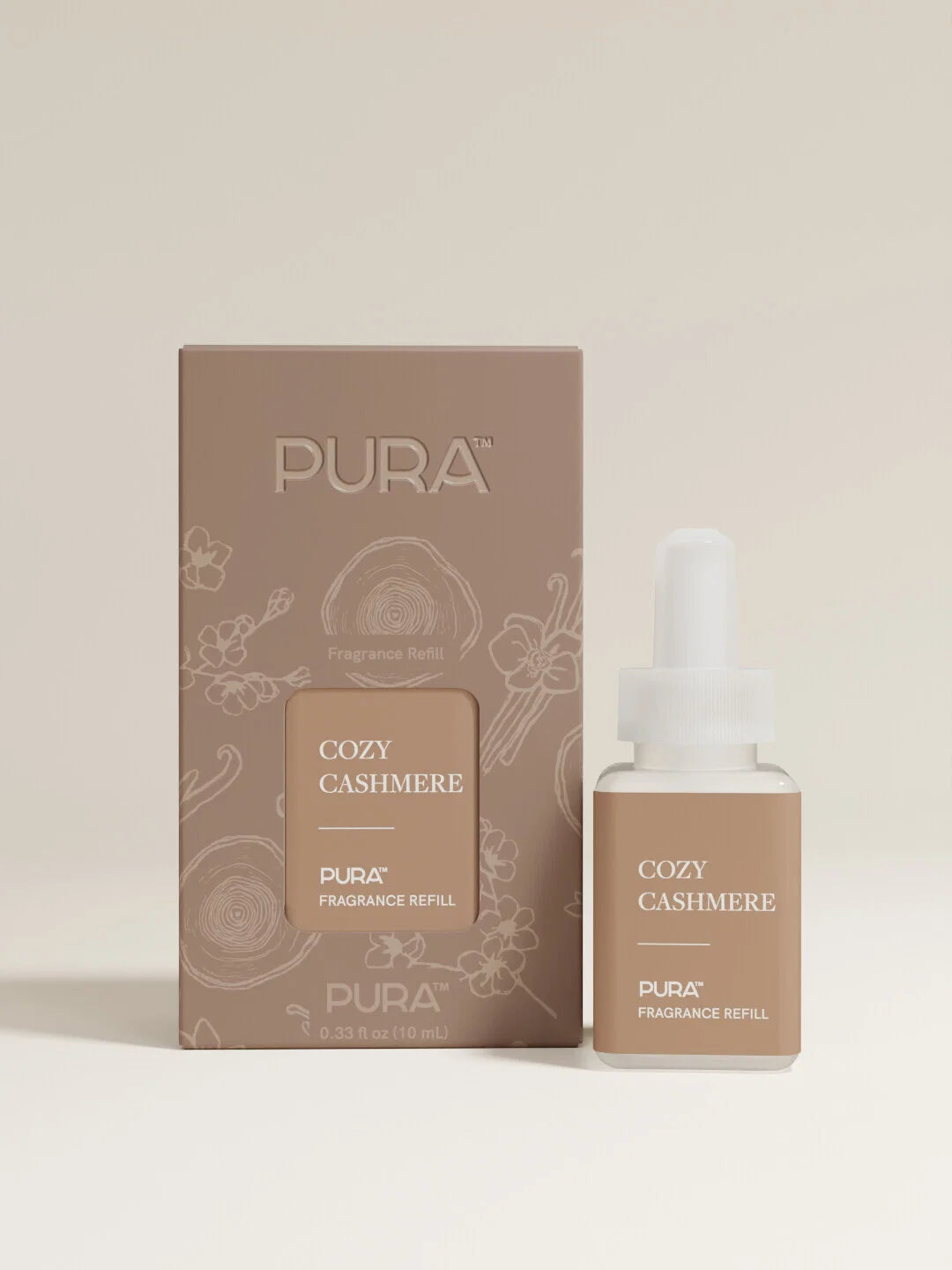 PURA Cozy Cashmere fragrance refill set, featuring a brown cardboard box and a matching dropper bottle with a white cap, set against a solid light beige background.