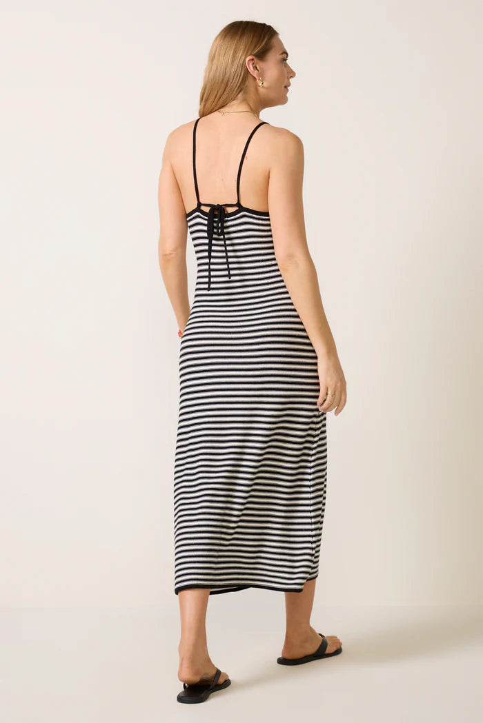 Woman wearing a black and white striped dress on a plain background