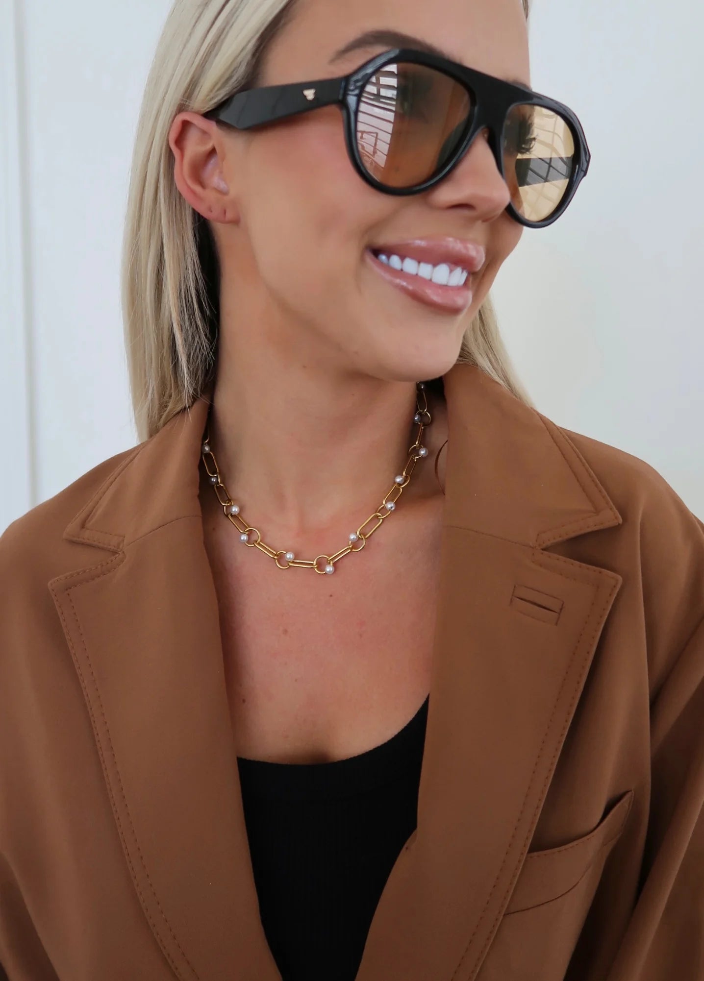 Woman wearing sunglasses and a brown coat with a white background