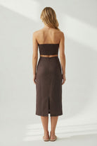Woman wearing a brown strapless top and skirt on a white background