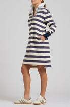 Person wearing a navy and white striped dress with a high collar on a plain background