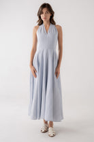 Woman wearing a light blue halter neck dress on a white background