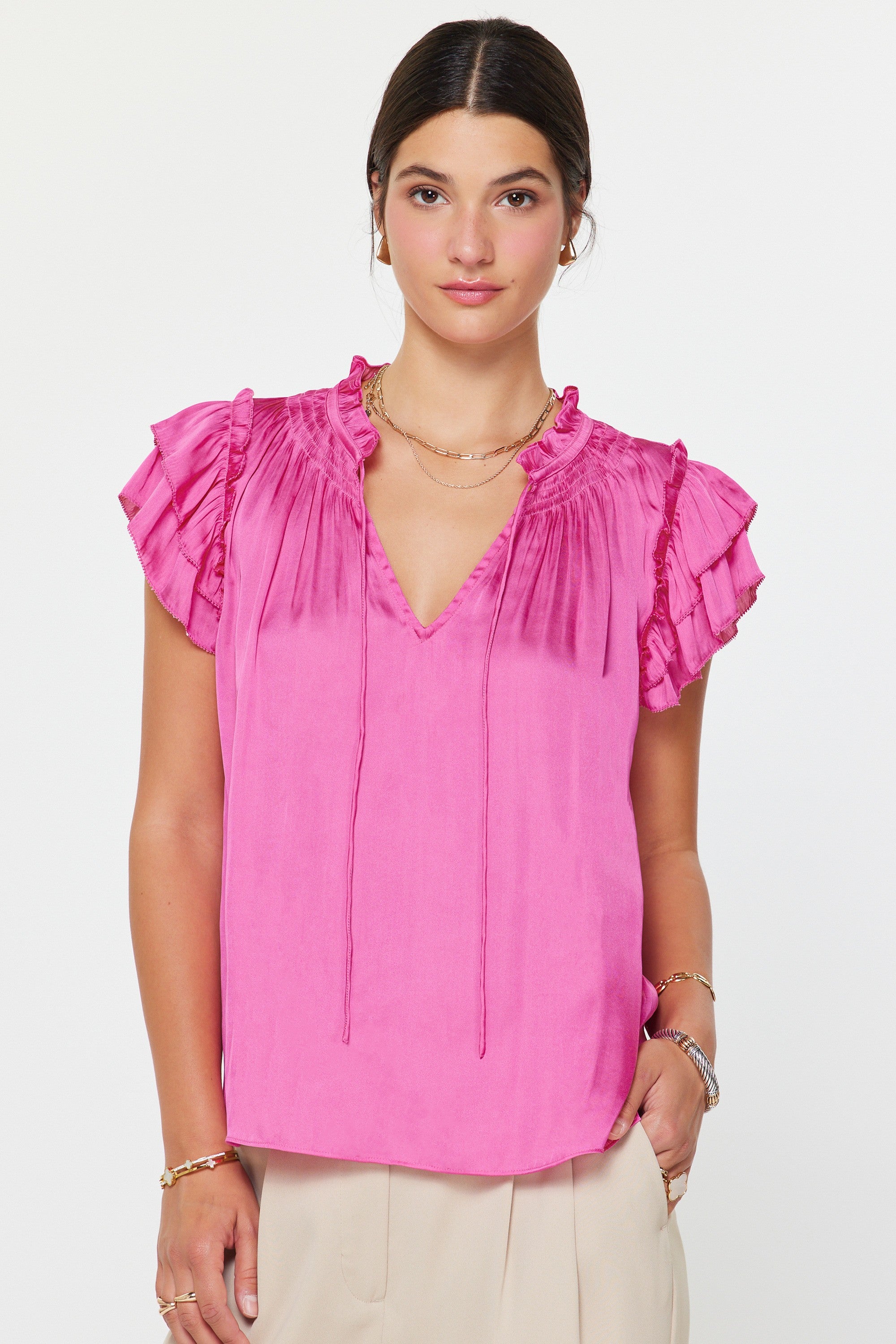 Woman wearing a pink blouse with ruffled sleeves on a white background