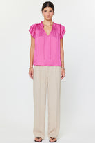 Woman wearing a pink blouse and beige pants on a white background