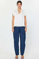 Woman wearing a white blouse and blue pants on a white background