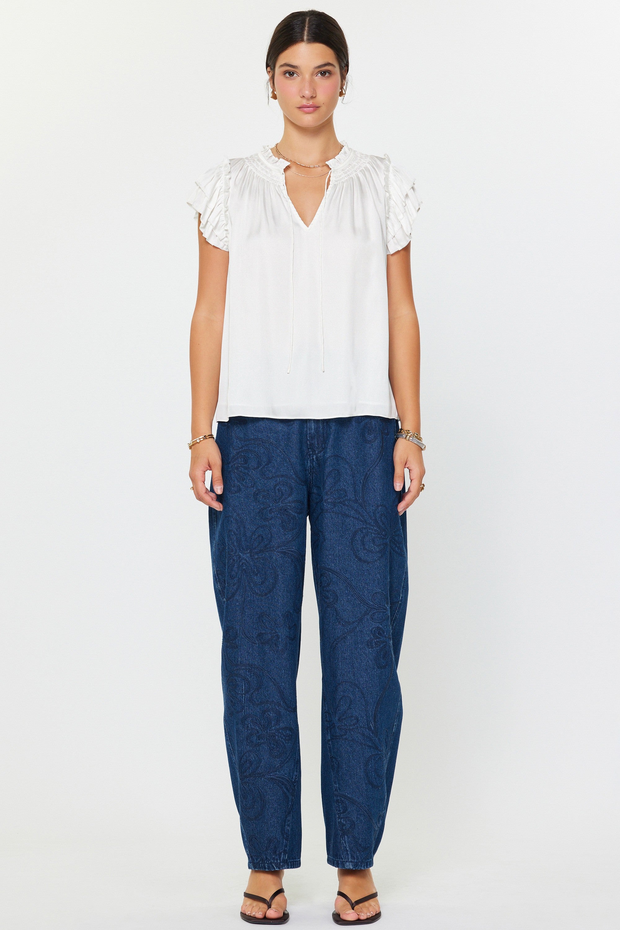 Woman wearing a white blouse and blue pants on a white background