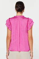 Pink blouse with ruffled sleeves worn by a person on a white background
