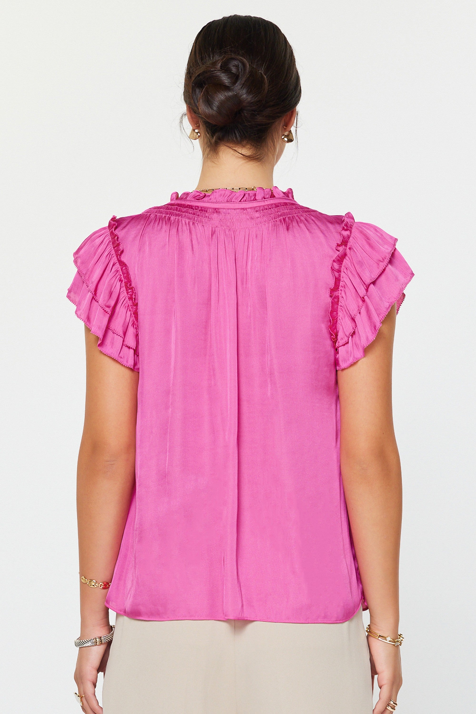 Pink blouse with ruffled sleeves worn by a person on a white background