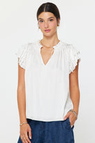 Woman wearing a white blouse with ruffled sleeves on a plain background