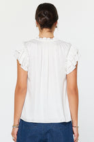 White blouse with ruffled sleeves worn by a person on a white background