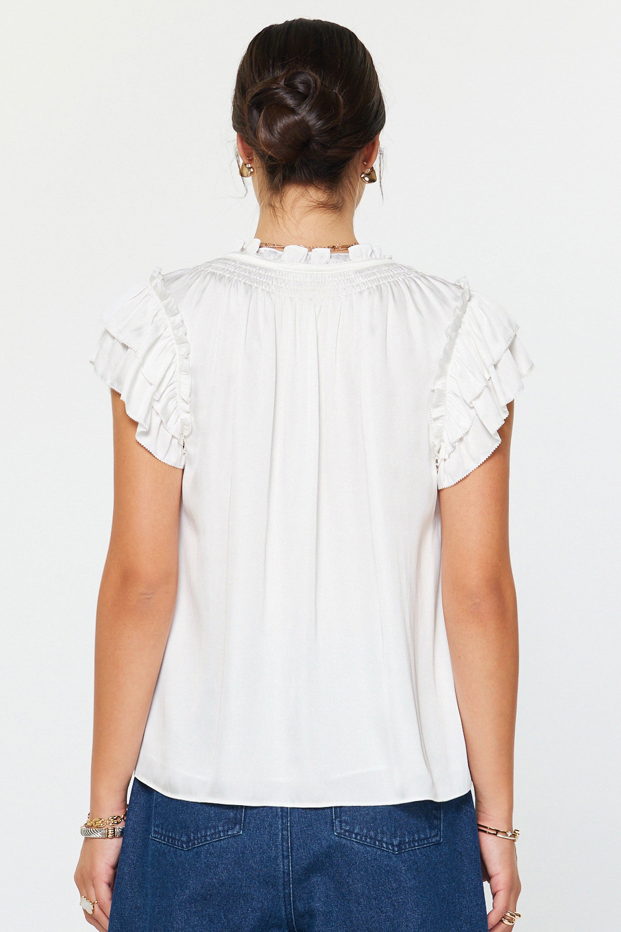 White blouse with ruffled sleeves worn by a person on a white background