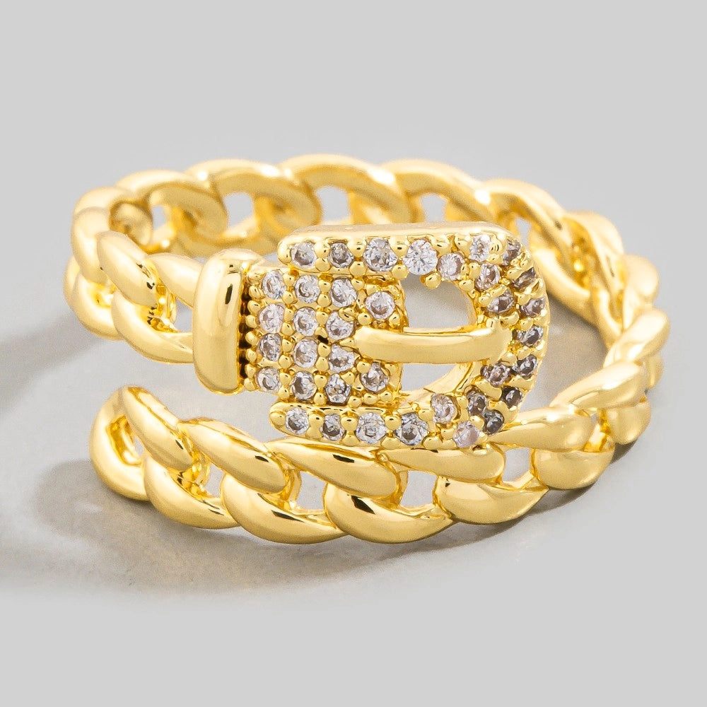 Gold chain ring with a diamond-encrusted belt buckle clasp on a light gray background