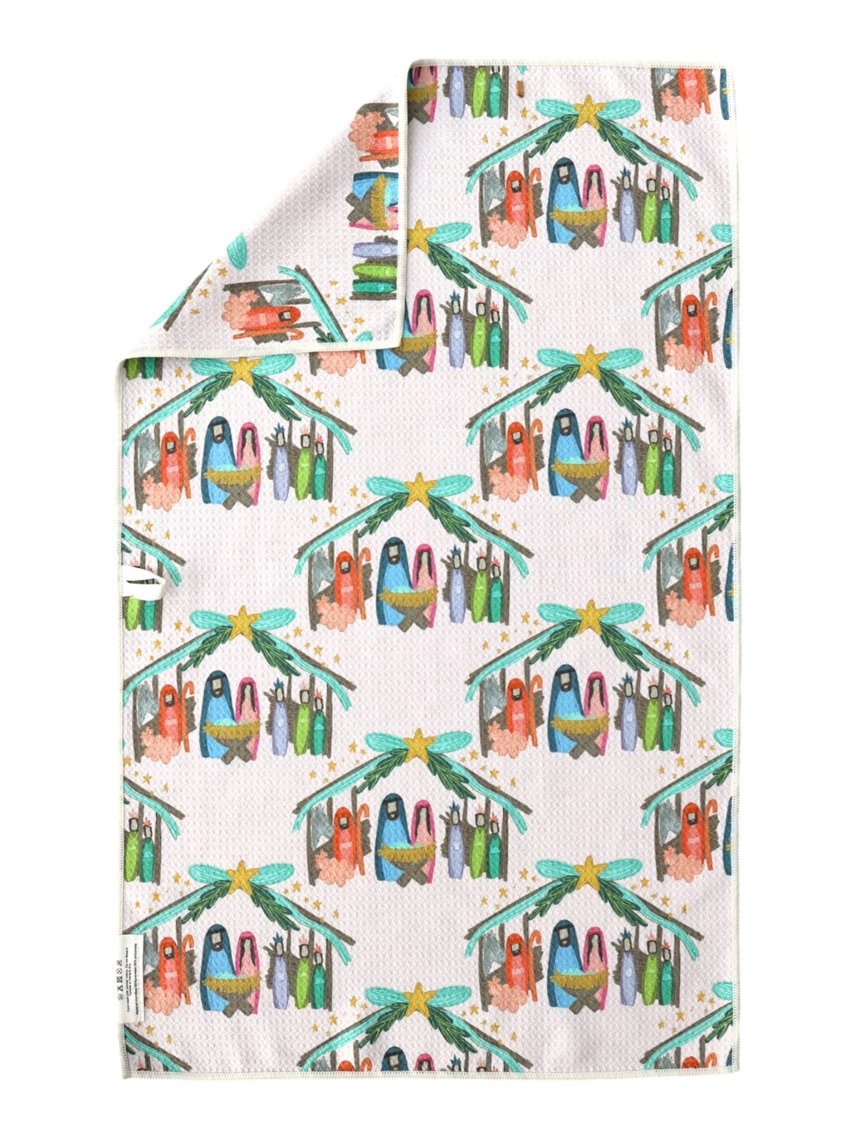 A folded white kitchen towel with a colorful Christmas nativity print, featuring penguins under starry roofs with green pine trees and teal bows.