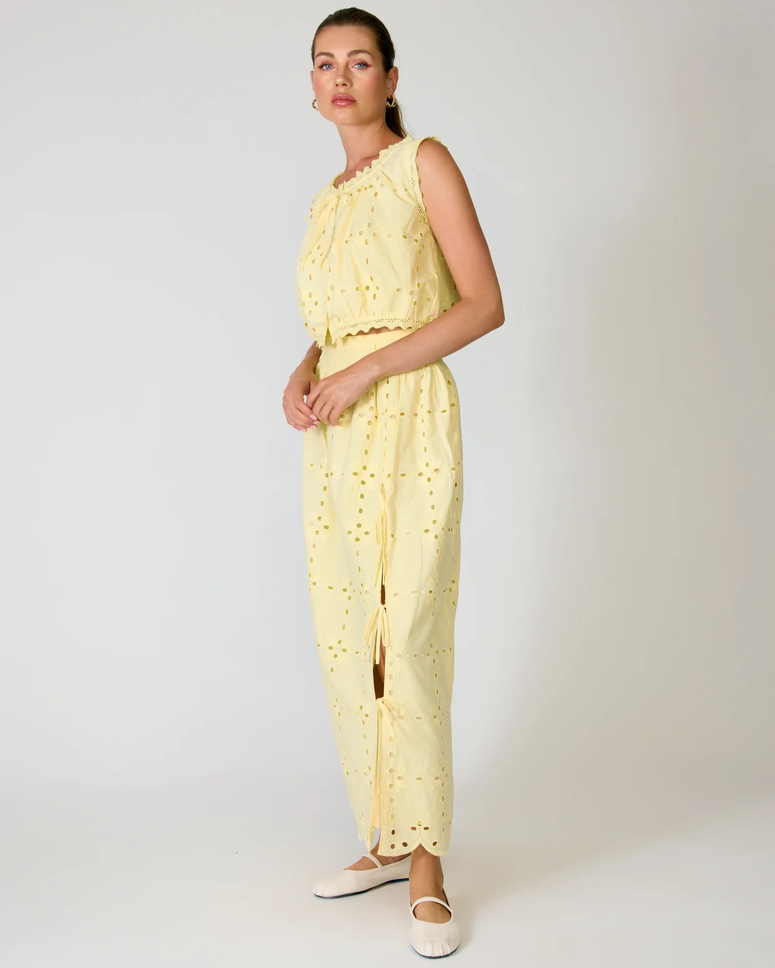 Woman wearing a yellow lace set against a white background