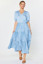 Woman wearing a light blue tiered dress on a white background