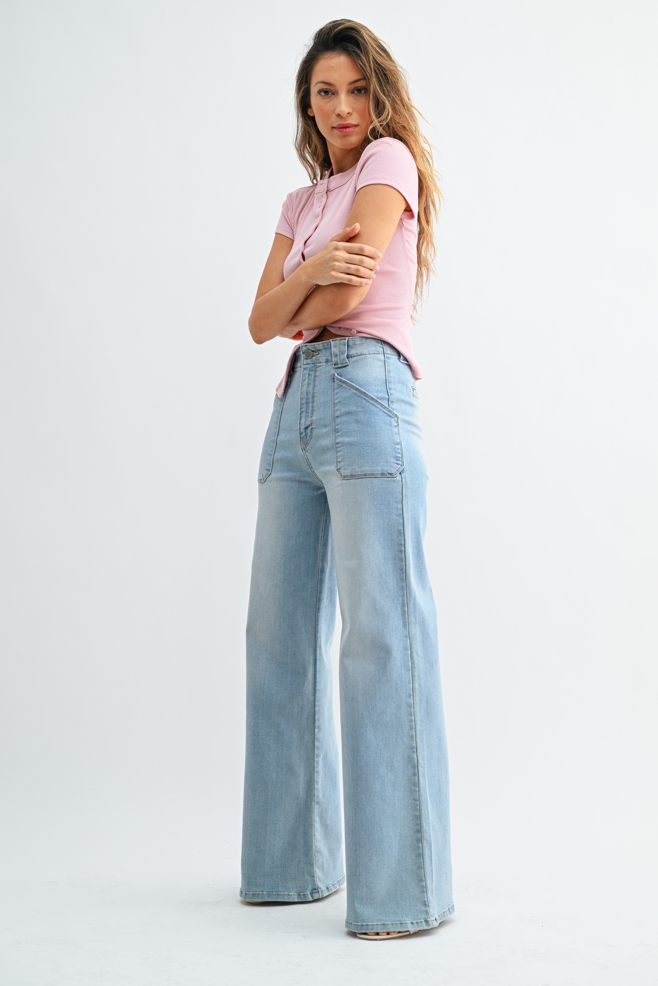 Woman wearing light blue jeans and a pink top on a white background