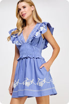 Woman wearing a blue dress with white embroidery on a white background
