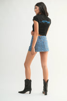 Woman wearing a black t-shirt with text and a denim skirt on a white background