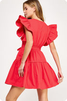 Woman wearing a red dress with ruffled sleeves on a white background