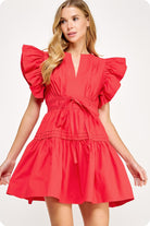 Woman wearing a red dress with ruffled sleeves on a white background