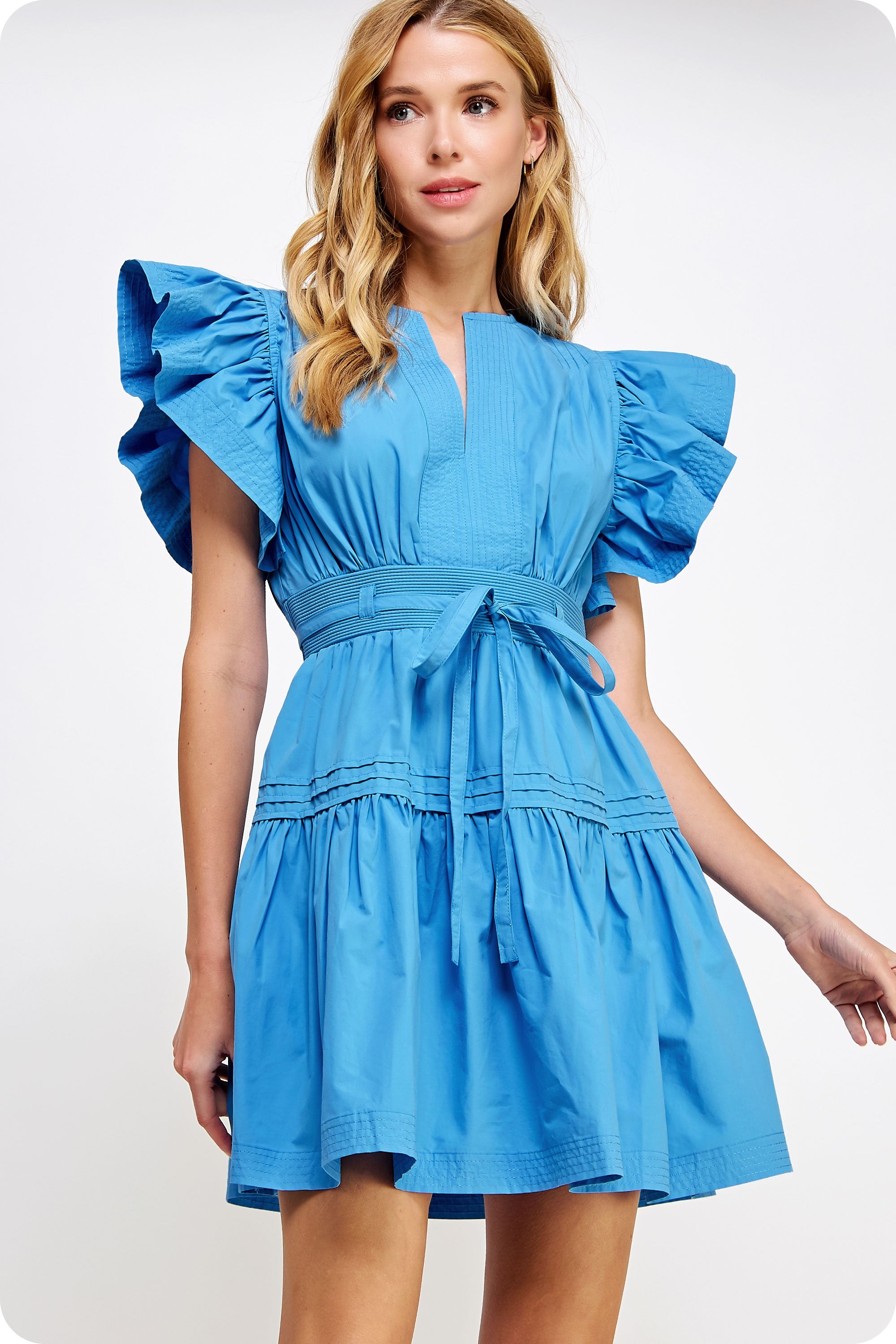 Woman wearing a blue dress with ruffled sleeves on a white background