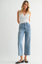 Woman wearing a white polka dot top and blue jeans on a white background