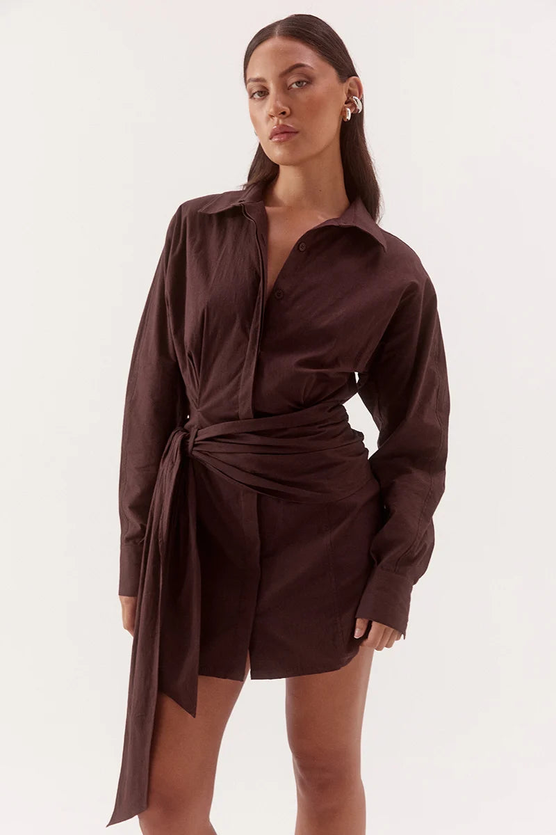 Woman wearing a brown shirt dress against a white background