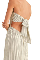 Woman wearing a striped halter top and wide-leg pants on a beige background