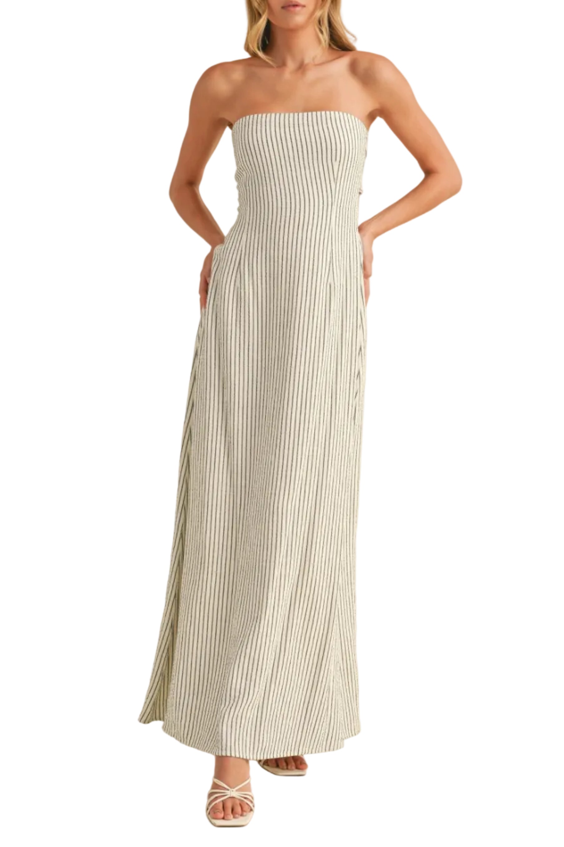 Woman wearing a strapless, long, white dress with black stripes on a beige background