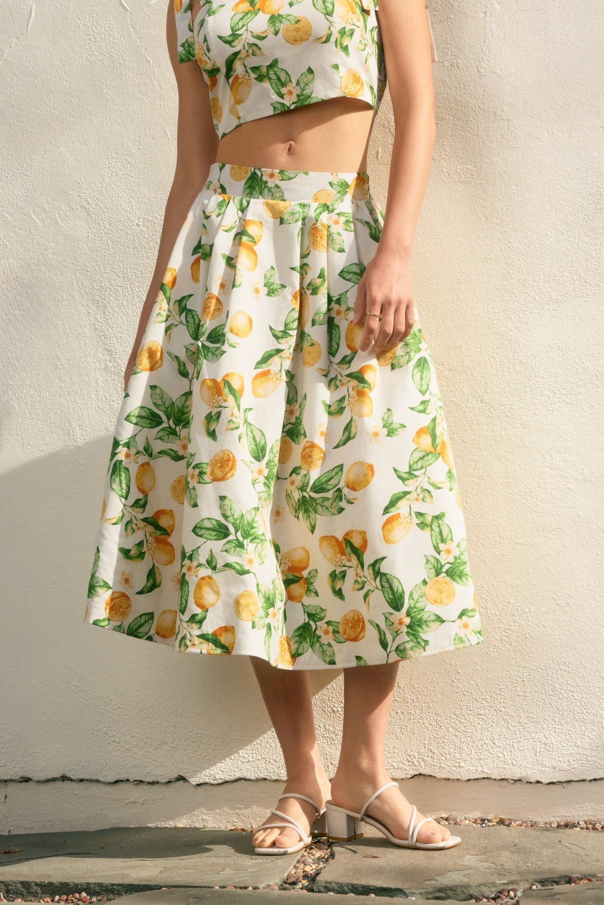 Person wearing a lemon print dress against a plain background