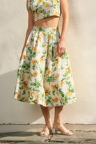 Person wearing a lemon print dress against a plain background