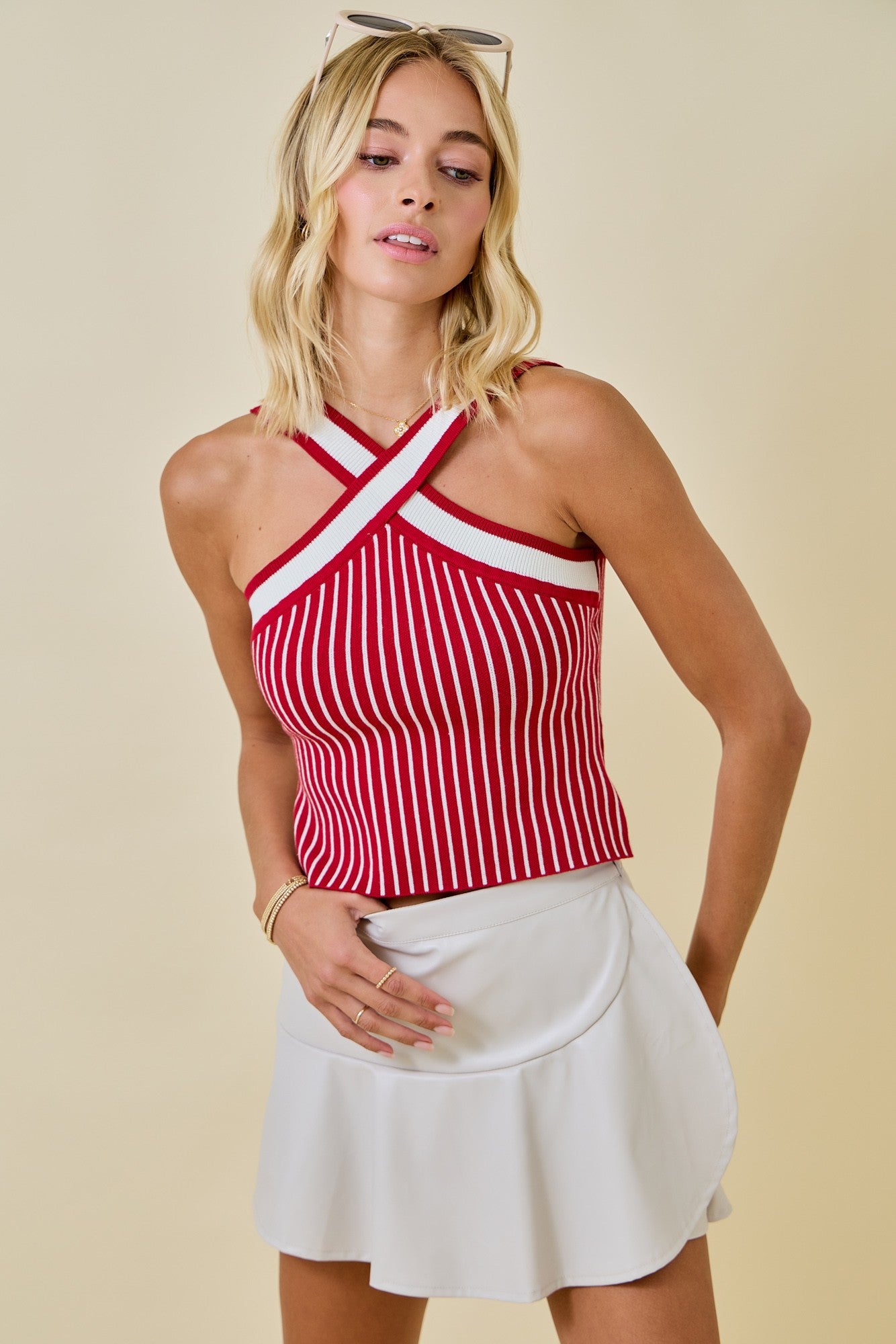 Woman wearing a red and white striped top with a white skirt on a beige background