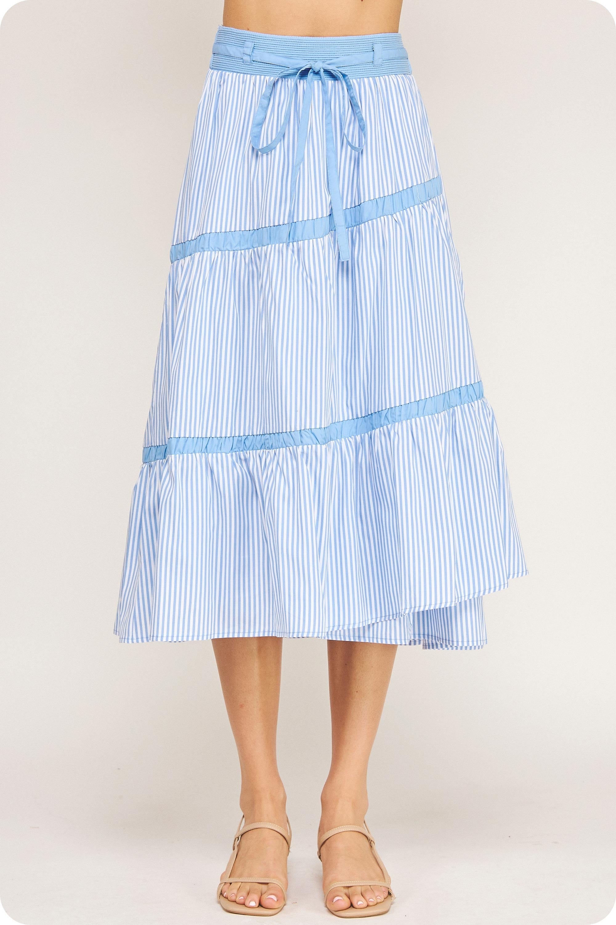Blue and white striped skirt worn by a person on a plain background