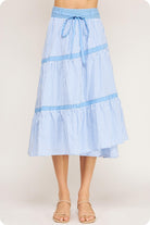 Blue and white striped skirt worn by a person on a plain background