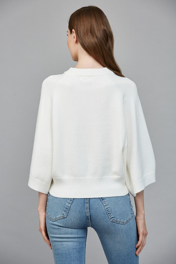 Person wearing a white sweater and blue jeans on a gray background