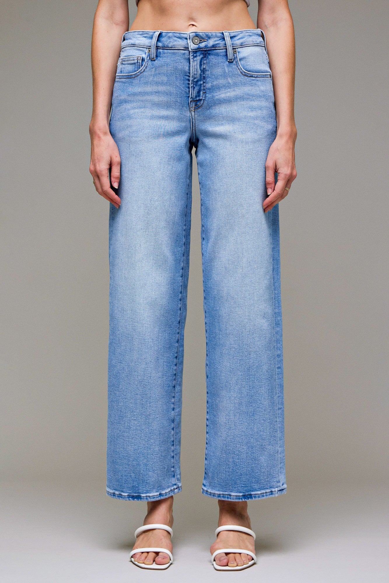 Person wearing light blue jeans on a plain background
