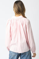 Person wearing a light pink blouse and blue jeans on a white background