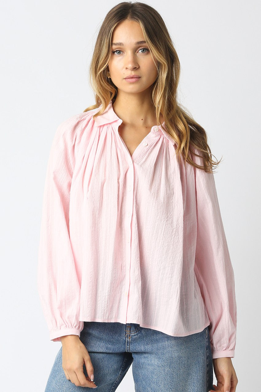 Woman wearing a pink blouse and blue jeans on a white background