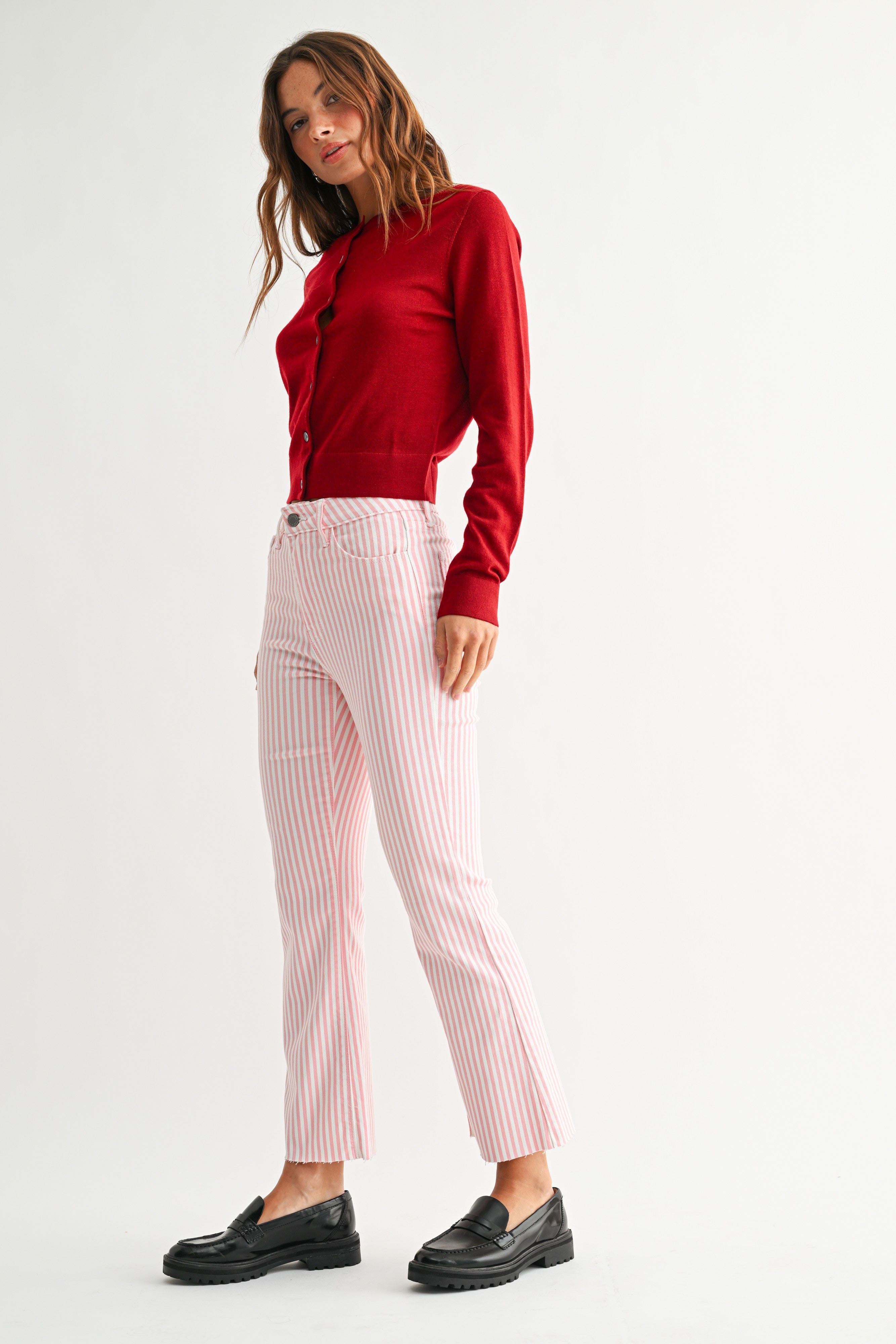 Woman wearing a red top and pink striped pants on a white background