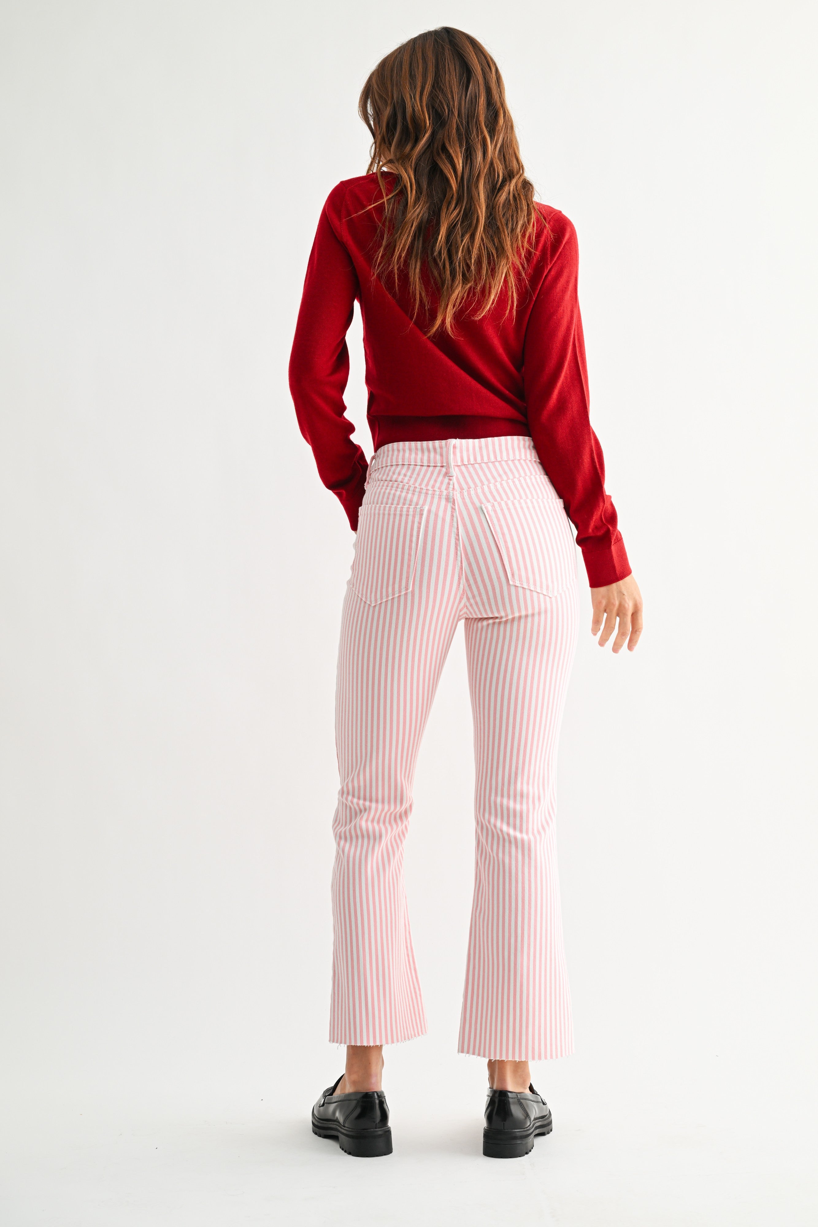 Person wearing a red sweater and pink striped pants on a white background