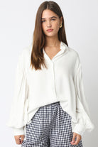 Woman wearing a white blouse and checkered pants on a plain background