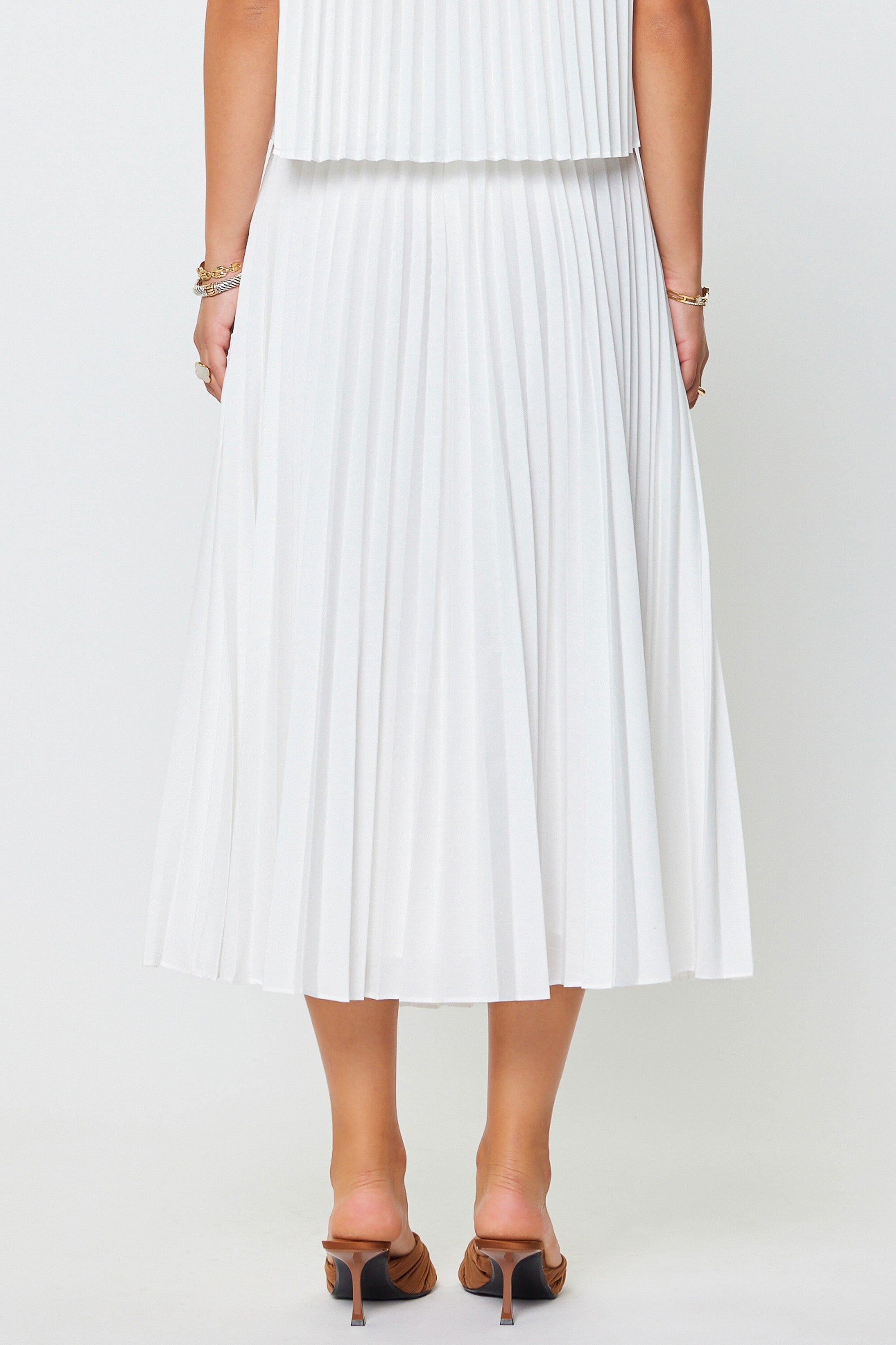 White pleated skirt worn by a person on a white background