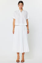 Woman wearing a white blouse and pleated skirt on a white background
