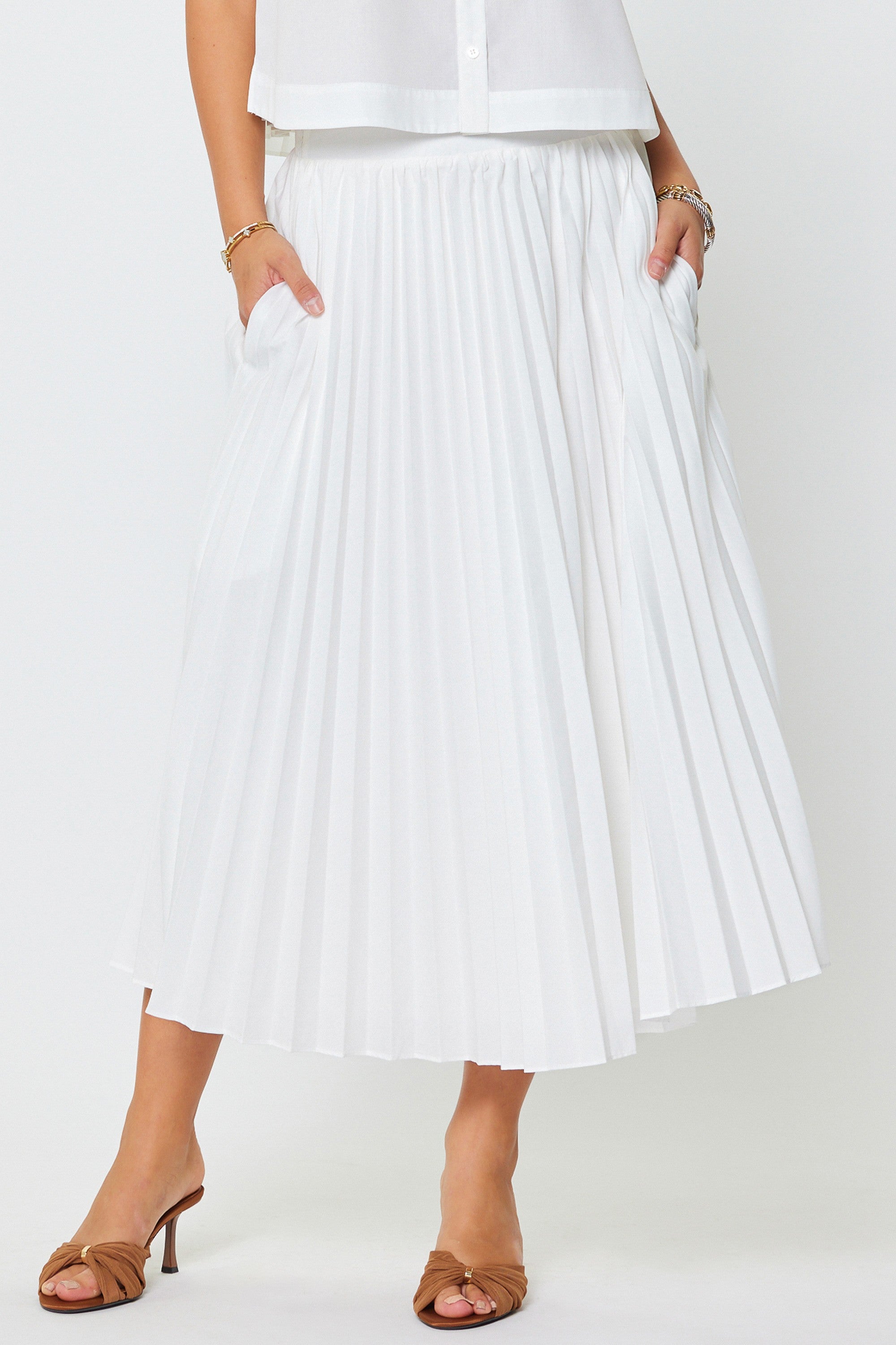 Person wearing a white pleated skirt on a plain background