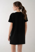 Person wearing a black t-shirt dress against a white background