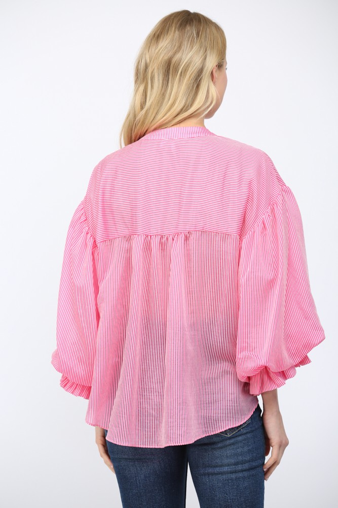Person wearing a pink checkered blouse with ruffled sleeves on a white background