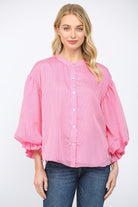 Woman wearing a pink striped blouse with balloon sleeves on a white background