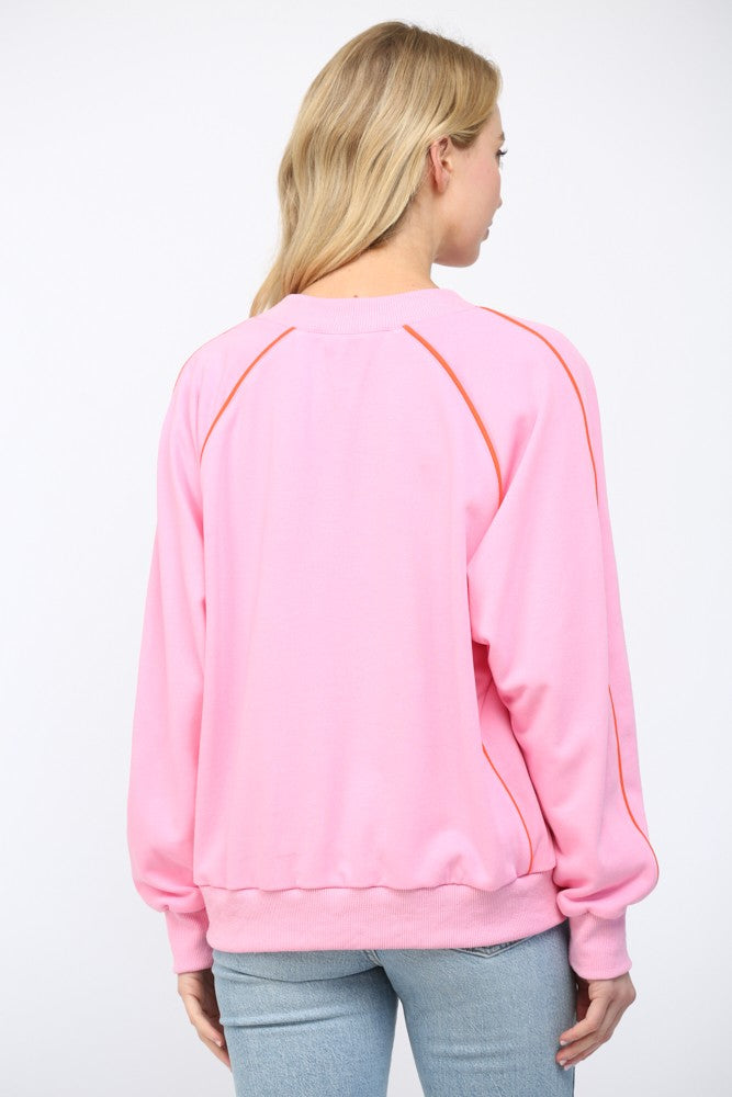 Person wearing a pink sweatshirt with orange accents on a white background